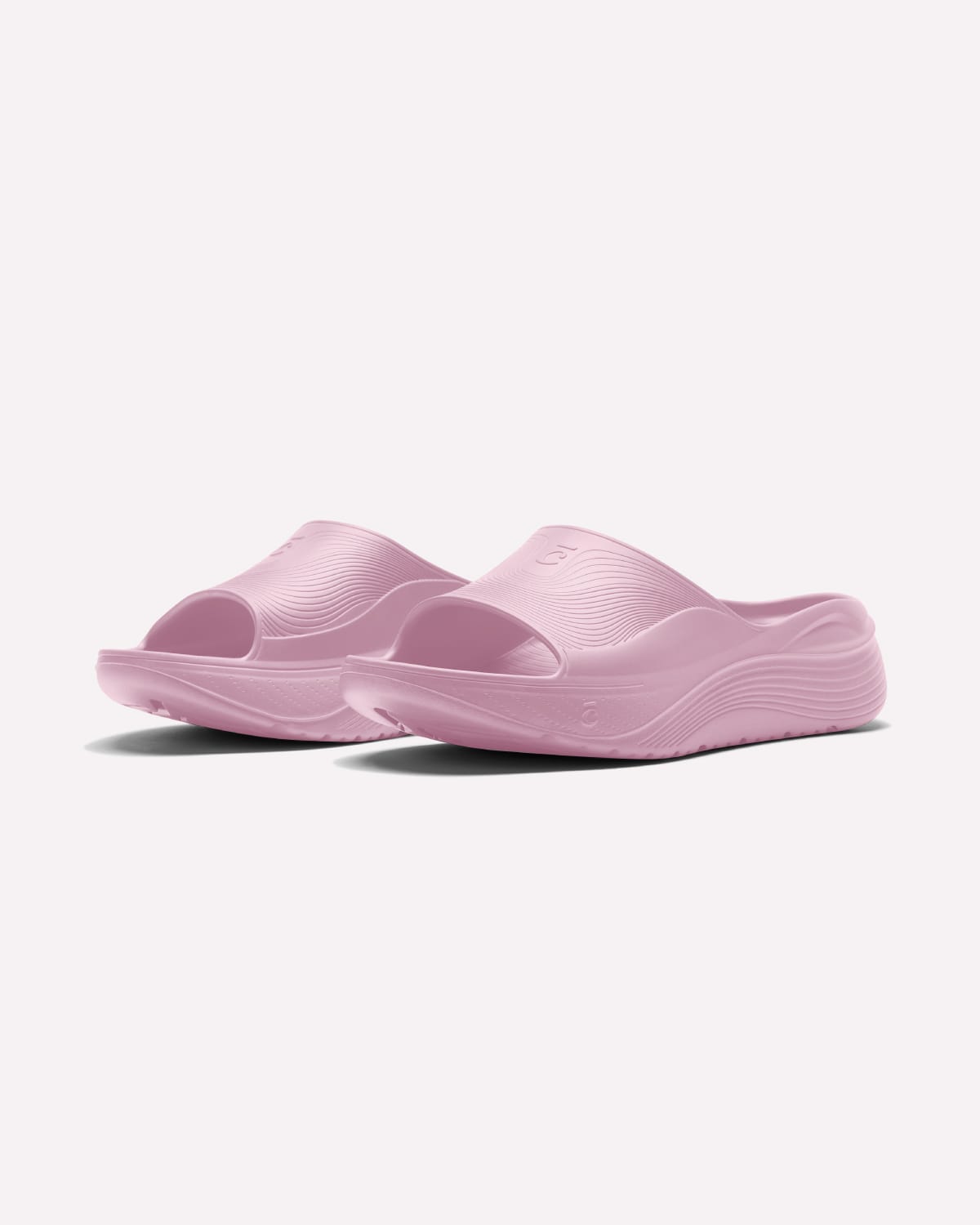 A pair of light pink molded slide sandals with open toes, shown on a clean off-white background.