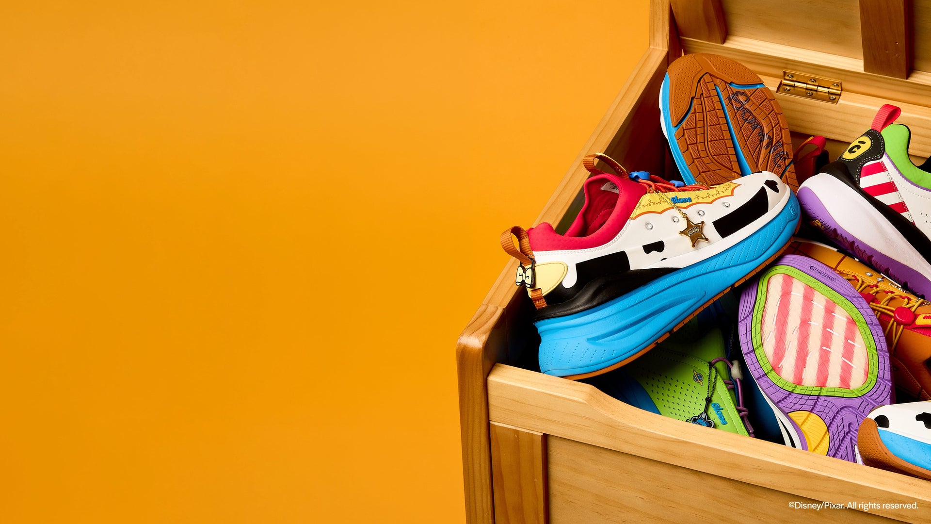 Colorful shoes in a wooden shoebox against an orange background