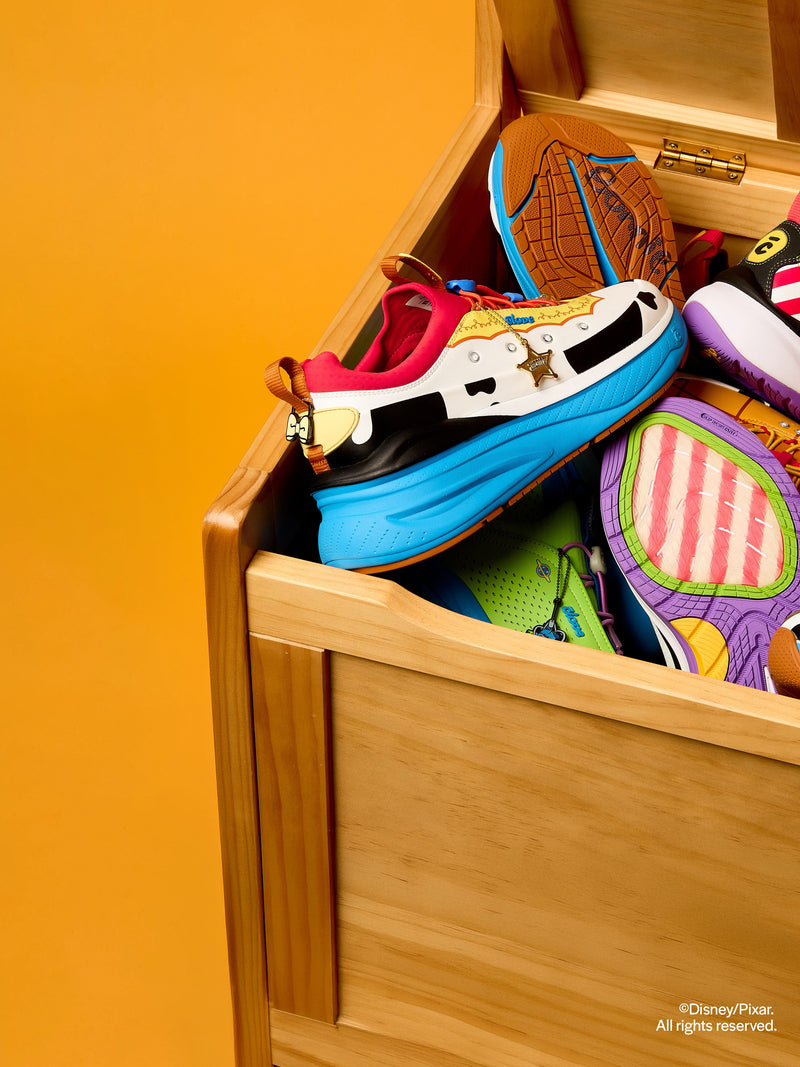 Colorful shoes in a wooden box against an orange background