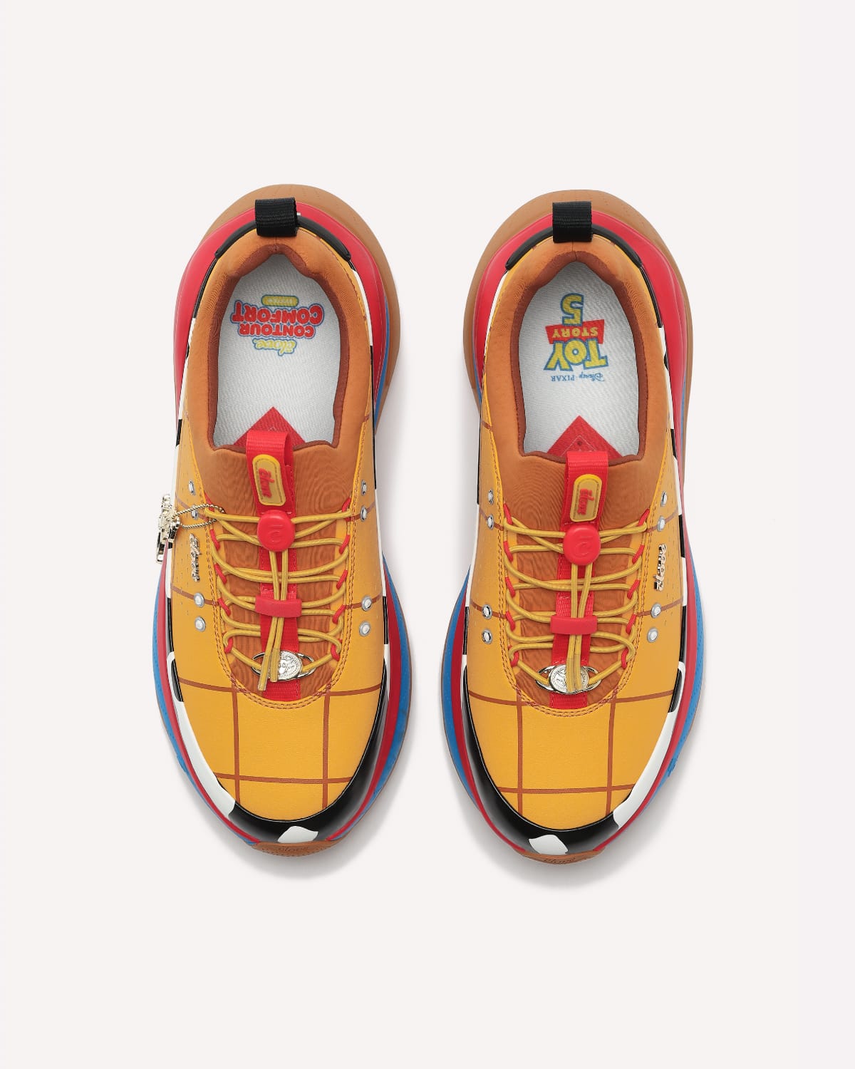 Pair of mustard yellow sneakers with red accents on a white background
