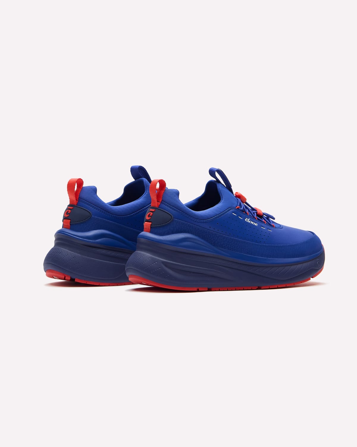 A pair of blue sneakers with red accents, including the bottoms, laces, and pull tabs, displayed on a clean off-white background.