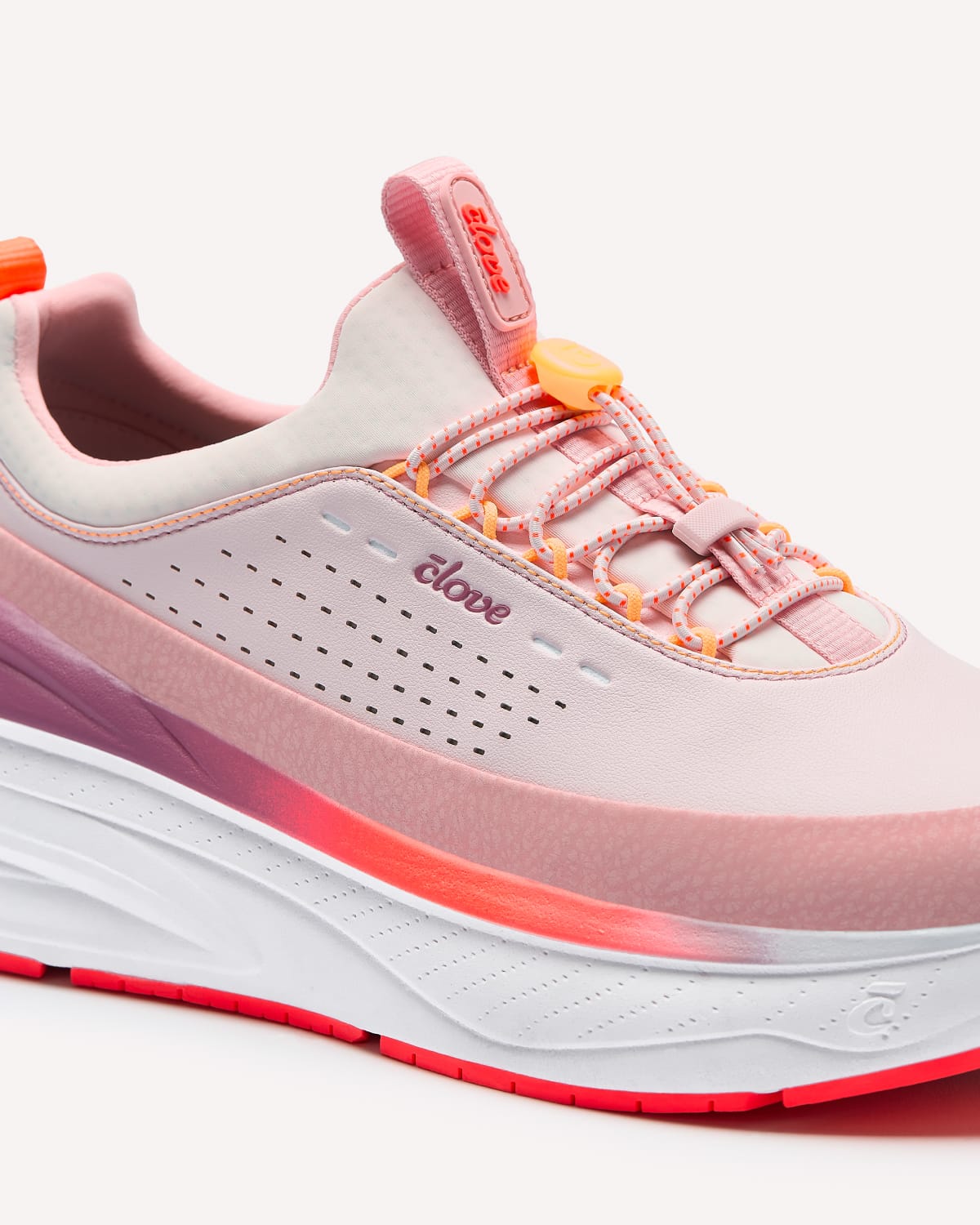Pink and white running shoe with orange accents on a light gray background