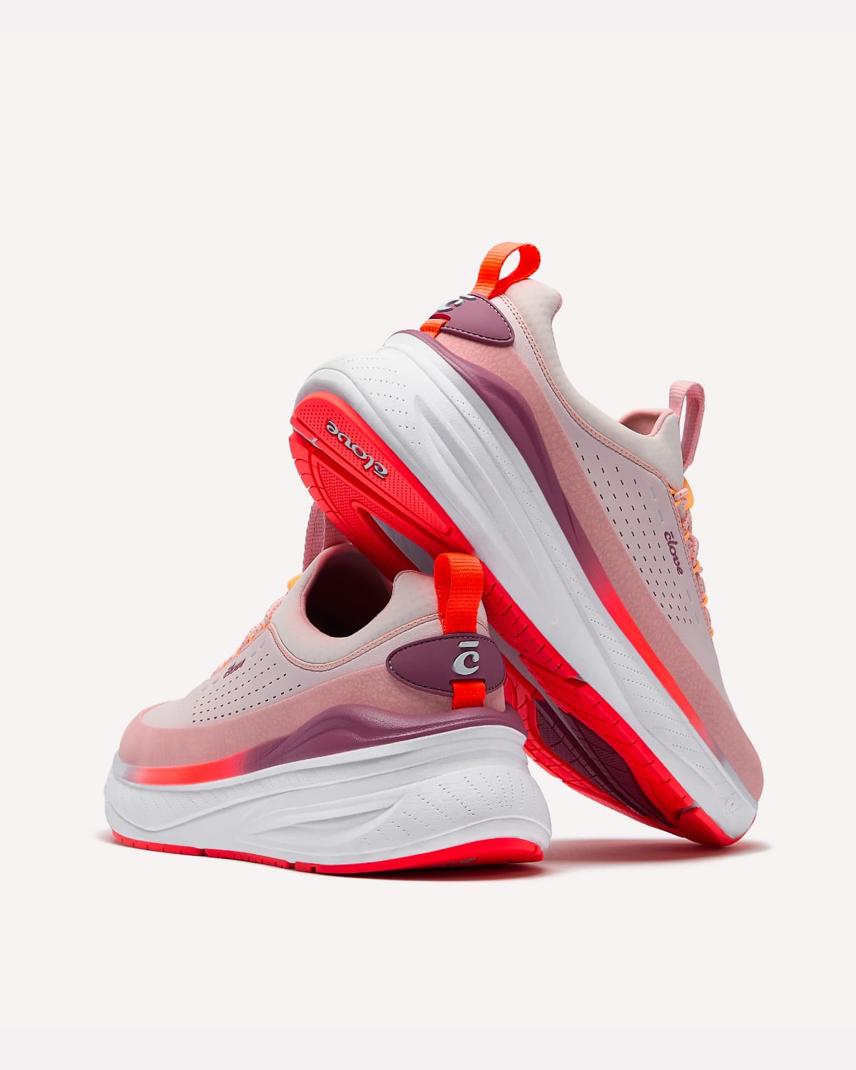 Pink and white running shoes with red accents on a white background