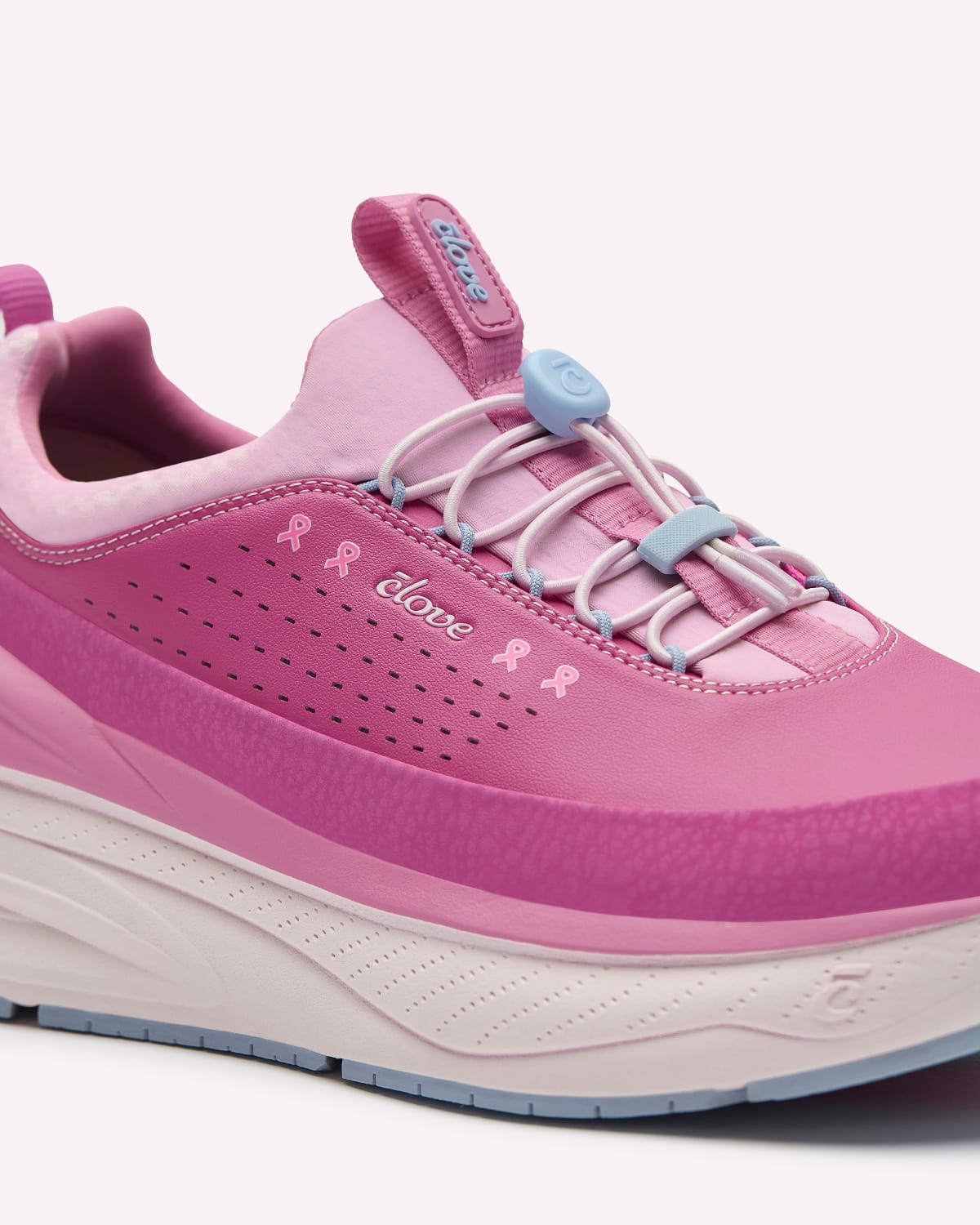 A pink athletic sneaker with a thick white and light blue bottom, featuring light blue laces with blue plastic tips and pink ribbon details on the side.