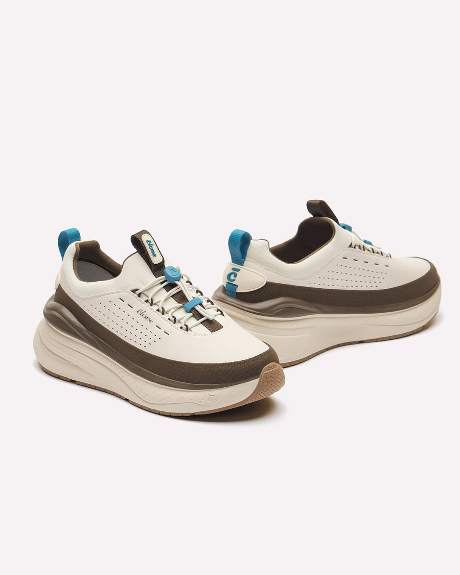 A pair of chunky platform sneakers in off-white, dark brown, and light blue, shown from a three-quarters angle on a light gray background.
