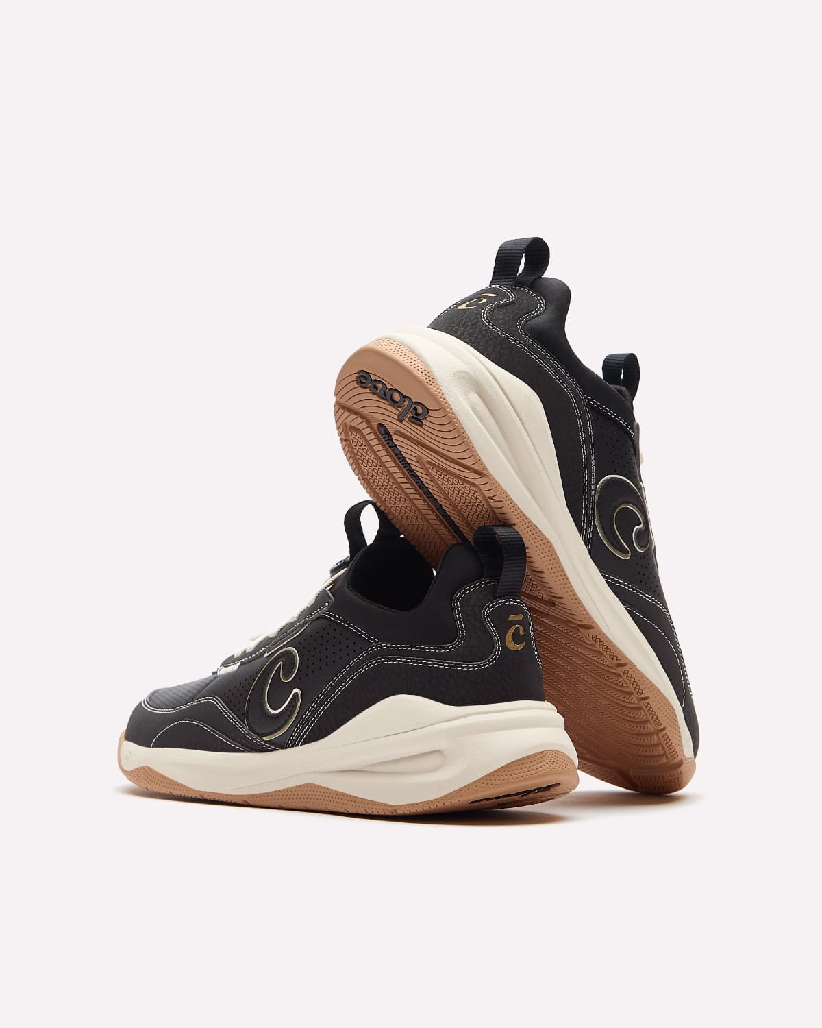 A pair of black sneakers with cream and gum bottoms, featuring the Clove C logo on the side and heel.