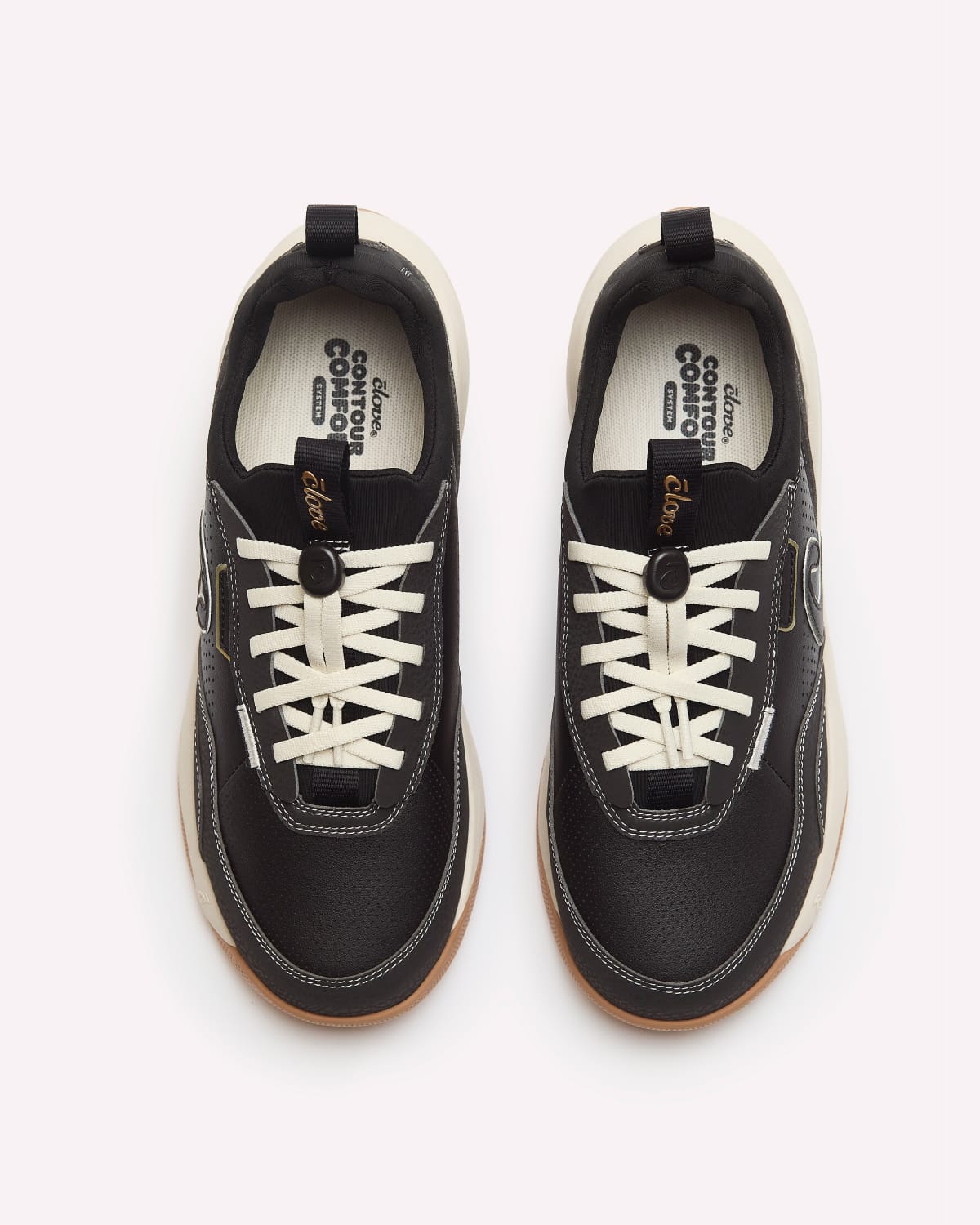 A pair of black low-top sneakers with white laces, a cream mid-section, and a gum bottom, shown from a top-down view on a light gray background.