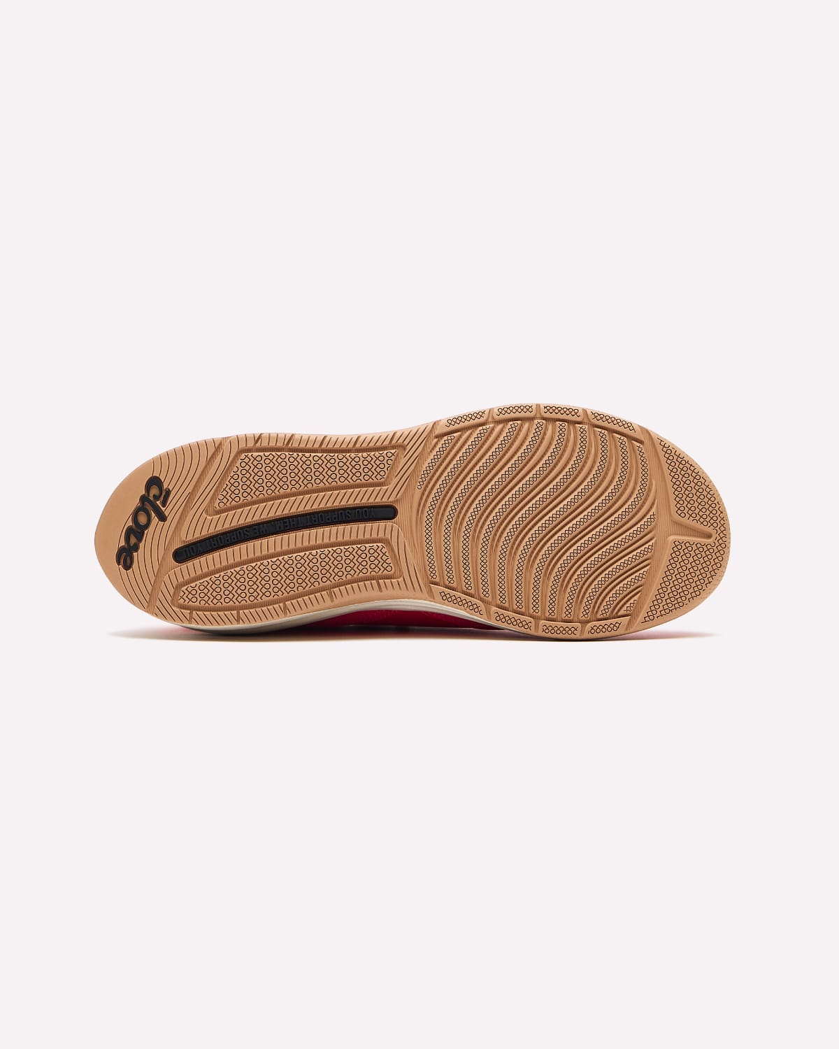 The outsole of a shoe in tan rubber with a black logo and a hint of red lining, shown against a light gray background.