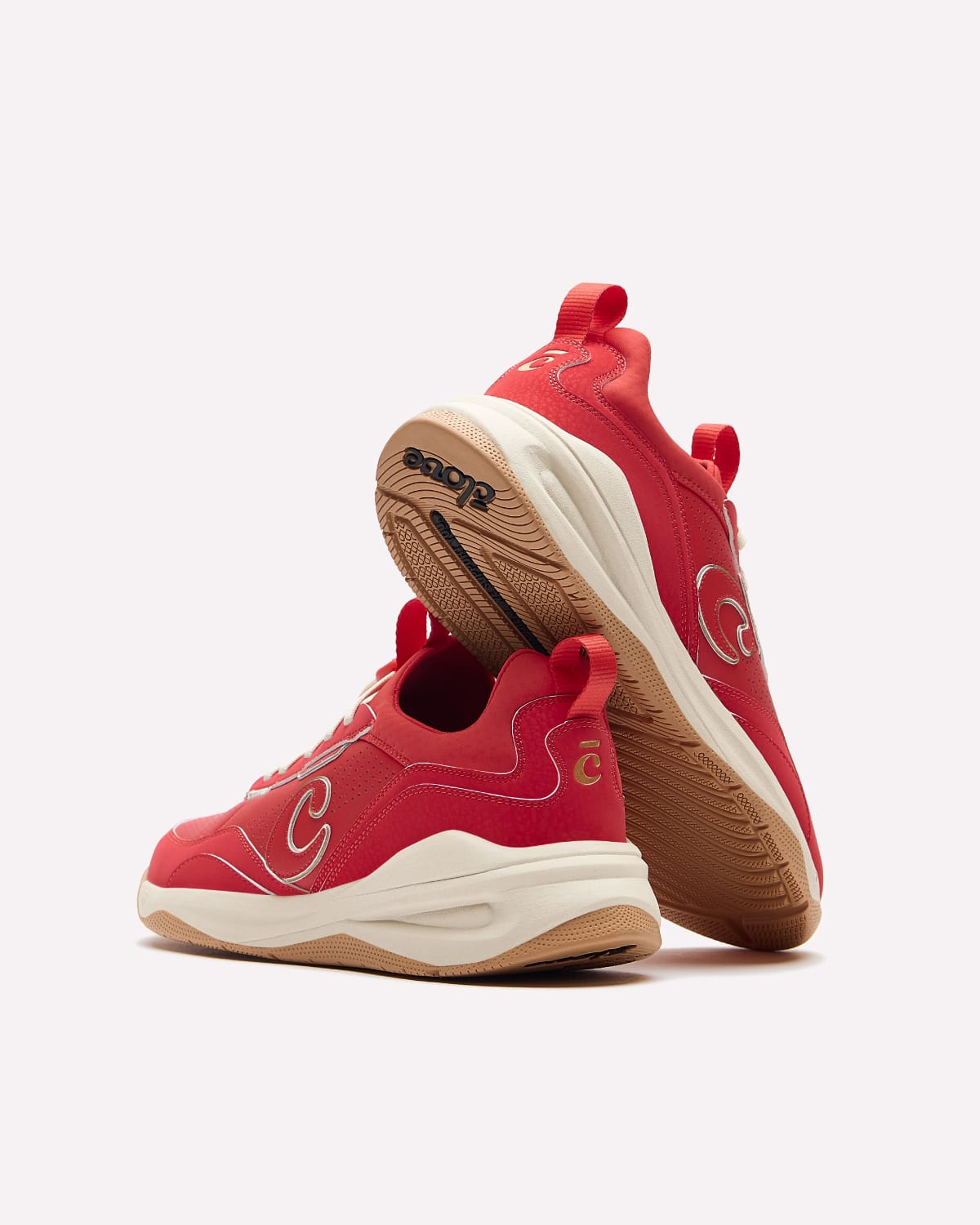 A pair of red and beige sneakers, with one shoe standing upright to show the bottom and the other lying flat to show the side profile. The brand name 'soar' is visible on the bottom.